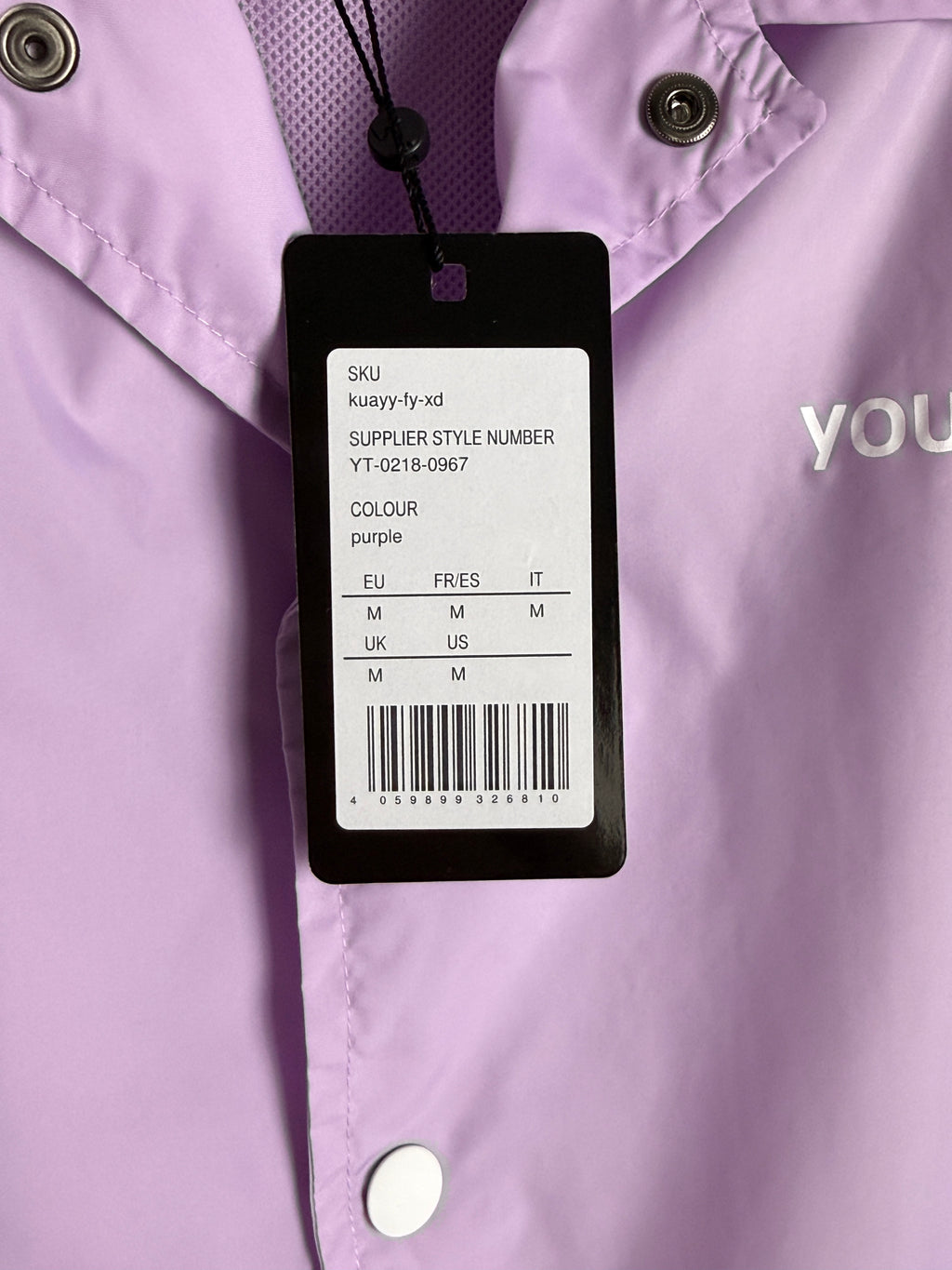 Close-up of a clothing tag on a purple garment with visible brand name.