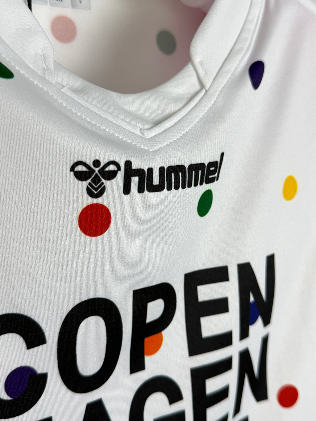 Close-up of a sports jersey with 'hummel' logo and colorful polka dots.