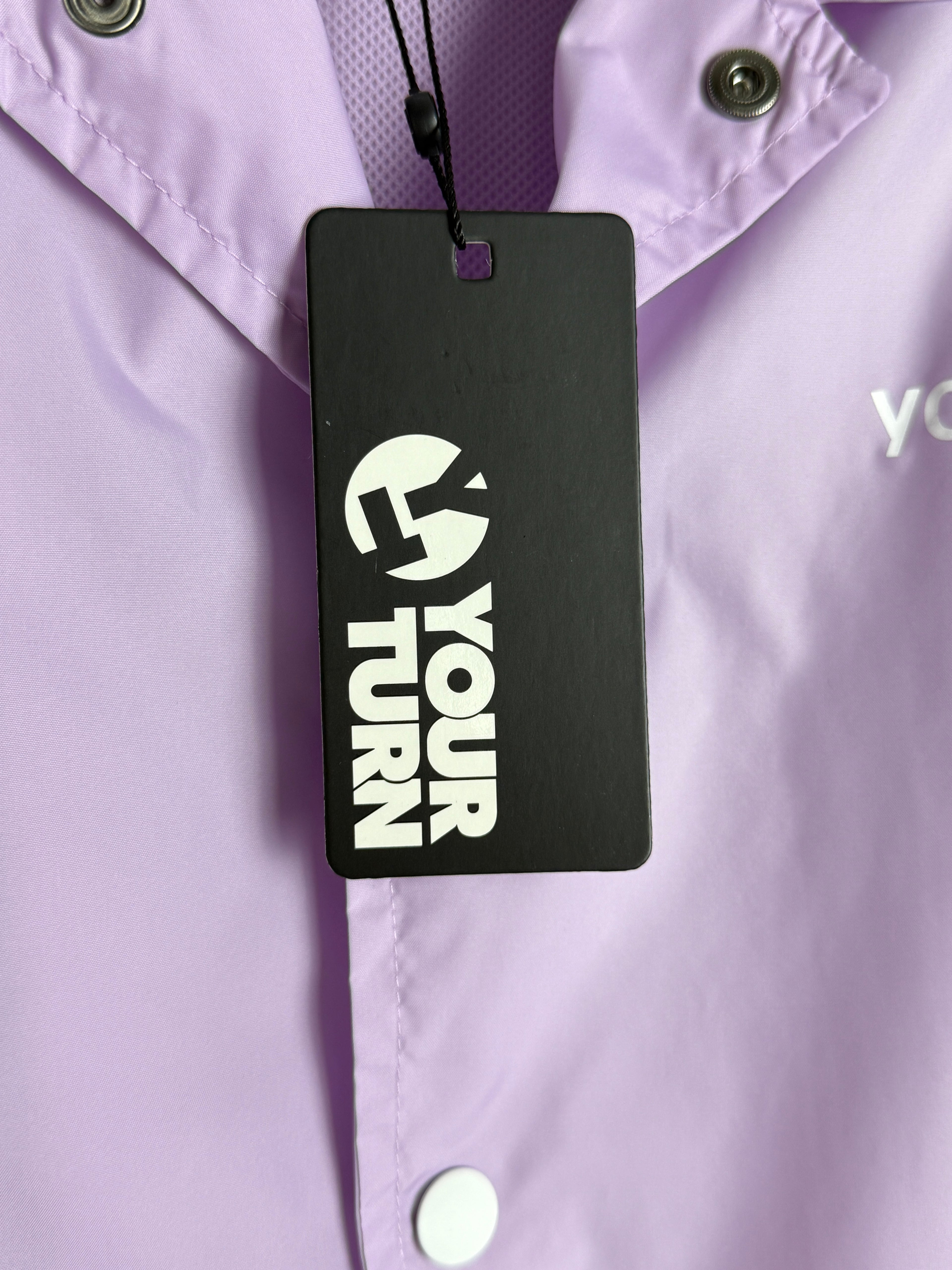 Black tag with 'Your Turn' text on a purple garment